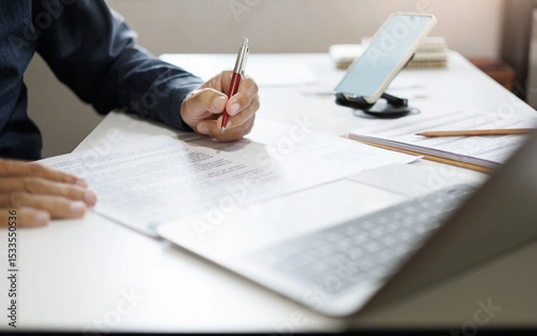 Fototapeta hand of businessman reviewing document at office. legal expert, professional lawyer working with computer reading and checking financial documents and business contract