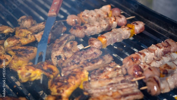 Obraz finishing touches to the almost cooked meat while everyone waits with their mouths watering