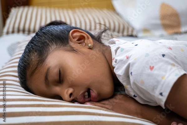 Obraz Child peacefully sleeping on a striped pillow in a cozy room