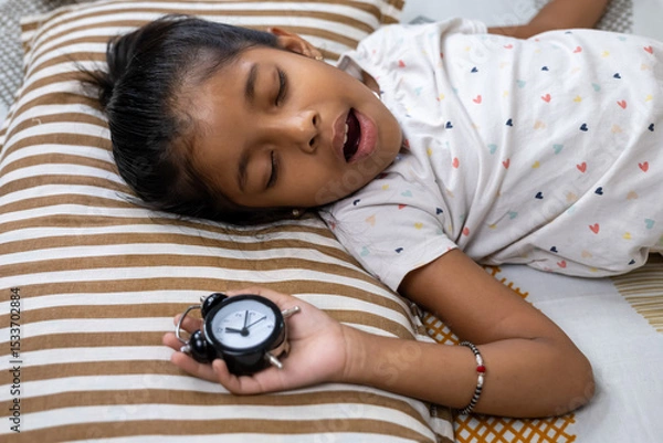 Obraz Child sleeping peacefully with alarm clock by side