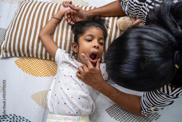 Obraz Child yawning while parent plays on a cozy bed