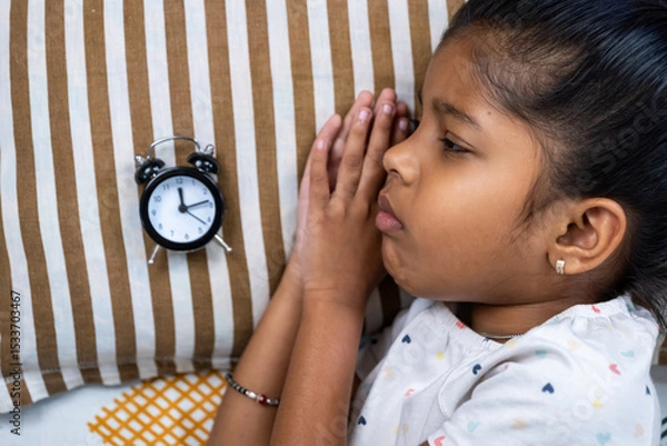 Obraz Girl waiting anxiously beside alarm clock on bed