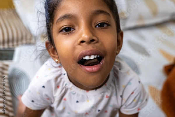 Obraz Smiling girl showing off her new teeth on a cozy bed