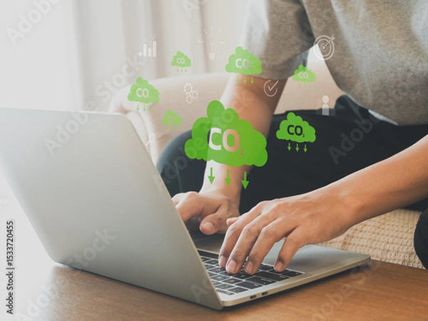 Fototapeta Person typing on laptop with green CO2 cloud icons representing carbon footprint reduction and environmental sustainability concepts