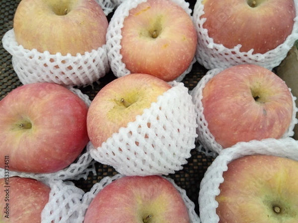 Obraz Apples wrapped in foam net are neatly arranged on supermarket shelves for sale