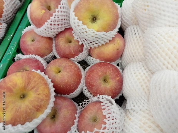 Obraz Apples wrapped in foam net are neatly arranged on supermarket shelves for sale