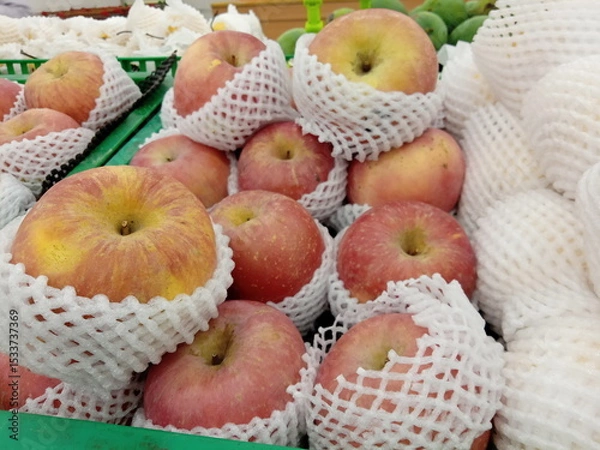 Obraz Apples wrapped in foam net are neatly arranged on supermarket shelves for sale