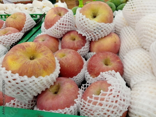 Obraz Apples wrapped in foam net are neatly arranged on supermarket shelves for sale
