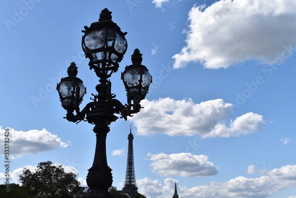 Obraz Lampadaire à trois lampes sous un ciel bleu, face à la Tour Eiffel.