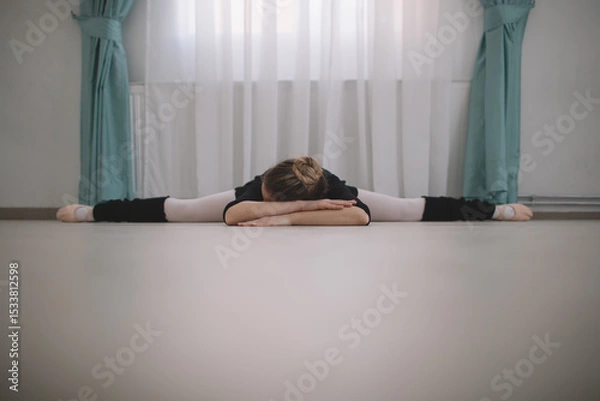 Fototapeta Ballet dancer stretching on the floor of dance studio