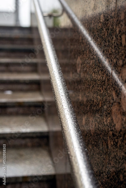 Fototapeta Round metal handrails at an underground passage exit glistening with raindrops after a fresh rainfall