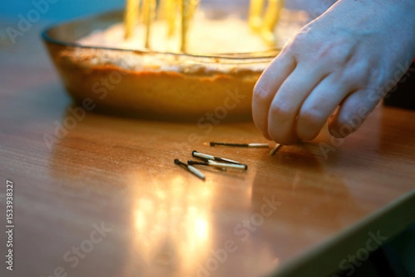 Fototapeta Burnt wooden matches arranged by hand near a festive cake with candle remnants, capturing a celebratory moment