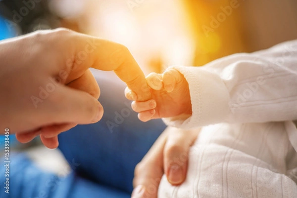 Fototapeta Newborn baby's tiny hand gripping father's finger, capturing a precious moment of bonding and connection