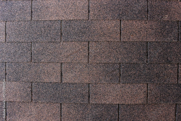 Fototapeta A close up, top down view of asphalt shingles, showcasing their granular texture and varying shades of dark brown and black.