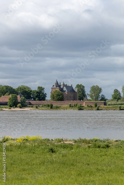 Obraz Loevestein Castle, a captivating medieval fortress in the Netherlands, seen across the river under a beautiful, cloudy sky.