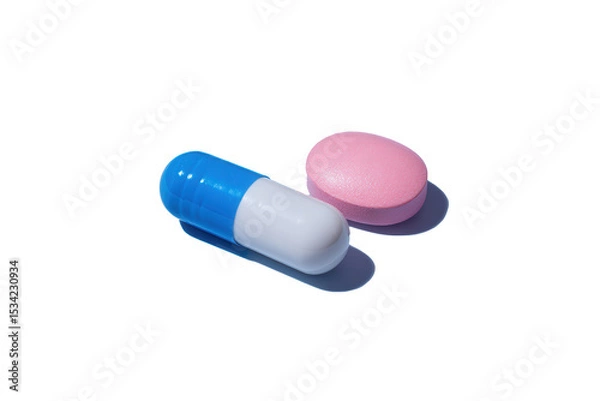 Fototapeta Vibrant blue and white capsule next to a soft pink tablet against a seamless backdrop creating a soothing contrast