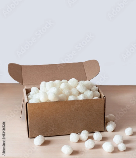 Fototapeta Biodegradable cornstarch packing peanuts filling an open cardboard box, safe product shipment while being environmentally friendly, practical and eco-conscious solution for modern packaging needs