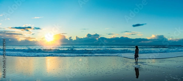 Obraz Silhouette eines jungen Mannes mit Hut bei Sonnenaufgang am Strand