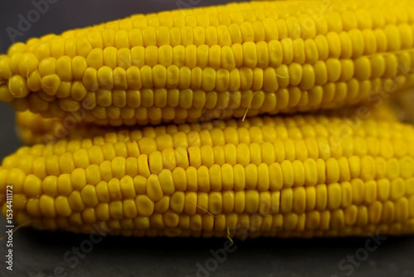 Fototapeta Close-up of yellow peeled corn cobs with a prominent texture of large grains lie on a dark background in the center. The concept of healthy nutrition, natural iron, corn cultivation. High quality