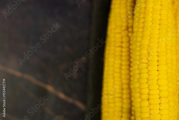 Fototapeta Close-up of yellow ripe peeled ears of corn with large grains lying on the side on a dark background with space for text. The concept of healthy nutrition, natural iron, corn cultivation. High quality