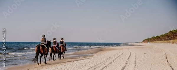 Fototapeta Wakacyjna letnia przygoda podczas obozu konnego dla dzieci i młodzieży podczas jazdy konnej w terenie. Grupowa wyprawa konno z instruktorem  na plażę nad morze w siodle.
