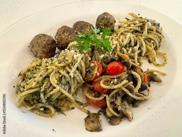 Obraz A delicious Pesto spaghetti with meatballs, mushroom, and tomato slices