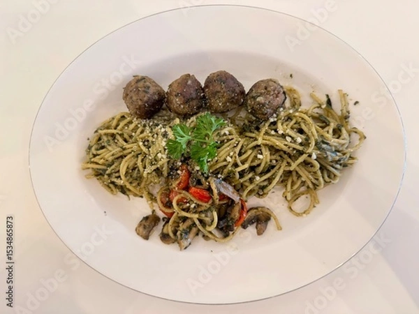 Obraz A delicious Pesto spaghetti with meatballs, mushroom, and tomato slices