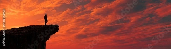 Obraz Silhouette of person standing on a cliff at sunset.