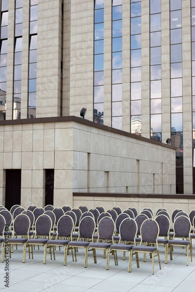 Obraz Chairs arranged in rows for a formal event against a backdrop of modern architecture.