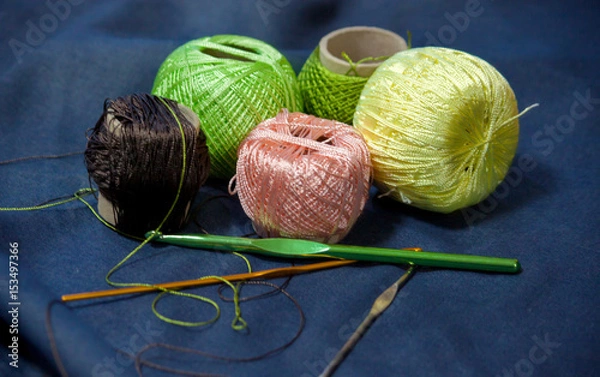 Obraz Entangled tangles of colored yarn for knitting and crochet hooks on a blue denim background