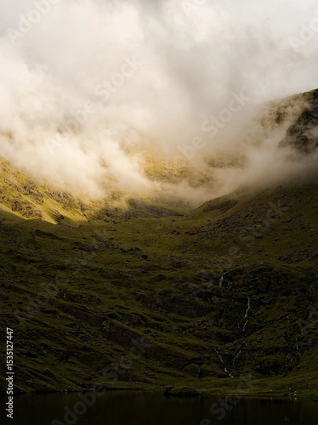 Fototapeta Green hills meet Lough Callee and the sky, covered in clouds, gives it a magical feel in Ireland.