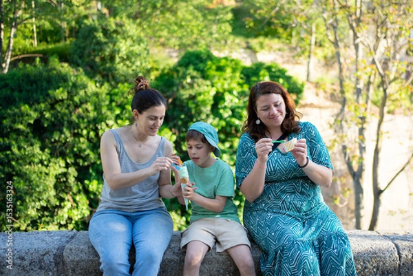 Fototapeta Family enjoying ice cream and snacks in park