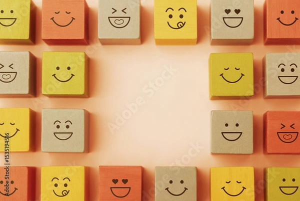 Fototapeta Happy Concepts. World Happiness Day, International Smiling Day. Mind and mental Health. Smiling Emoticon Face on Yellow Orange Cube. Table Top View with Copy space