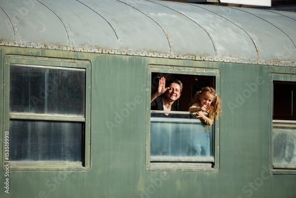 Obraz Mother with kid wave from train window in warm afternoon light