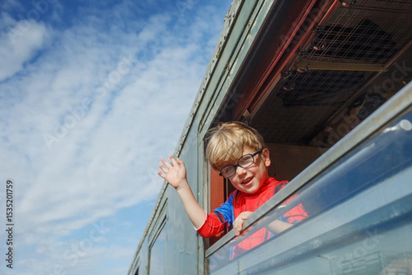 Obraz Boy waves cheerfully from green coach window at bustling station