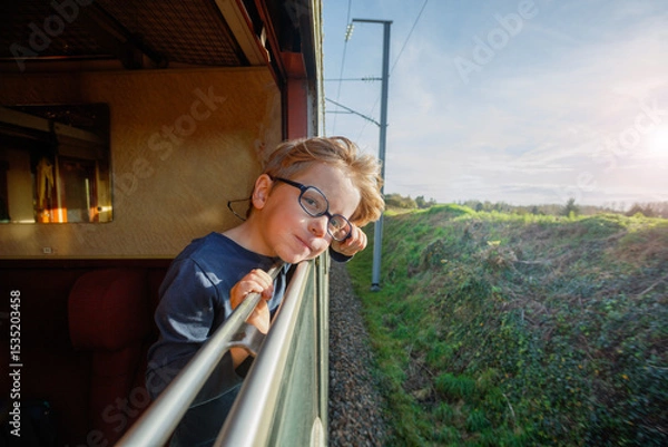 Obraz Smiling boy leans out carriage window against fields backdrop