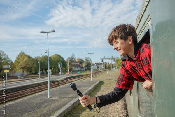 Obraz Boy films passing landscape with stick through train carriage