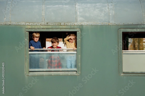 Obraz Three children lean from train window pointing at countryside