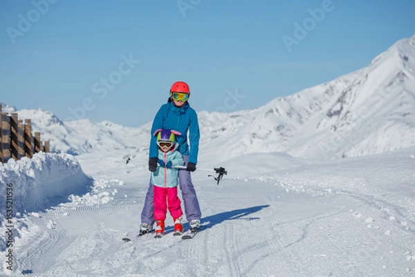 Obraz Adult and little kid skiers slide together in mountain landscape