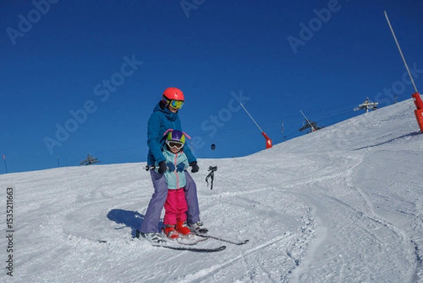 Obraz Instructor and kid girl on flat slope train to make ski turns