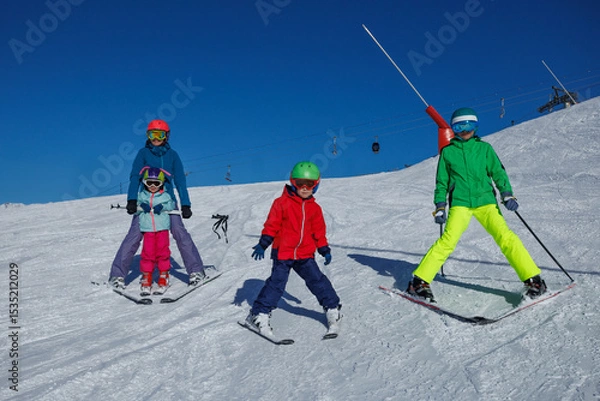 Obraz Young skier in red jacket glides down slope under vivid blue sky