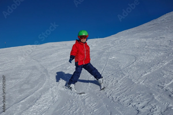 Obraz Young skier in red jacket practices wedge turns on a snowy slope