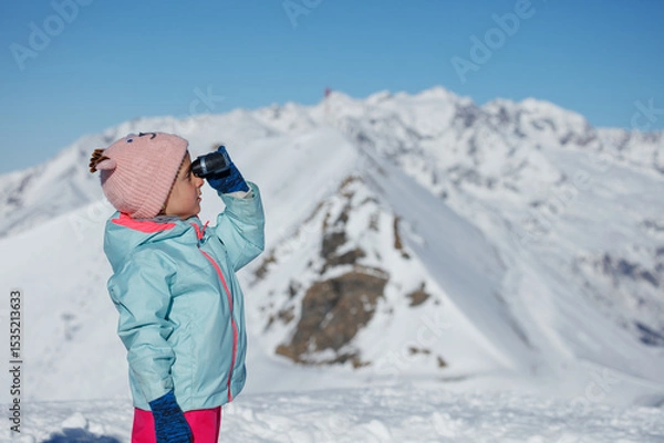 Obraz Kid in winter wear enjoys snowy mountain view through binocular