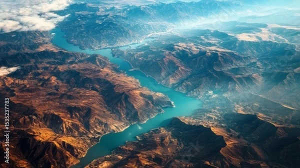 Obraz Aerial view of a winding river flowing through rugged mountains, showcasing vibrant blue waters and earthy tones of the landscape, capturing the beauty of nature's topography