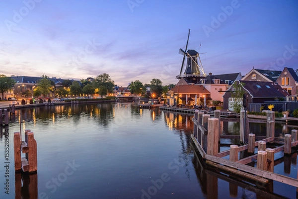 Fototapeta Windmill de adriaan and cityscape reflections on spaarne river in haarlem, netherlands