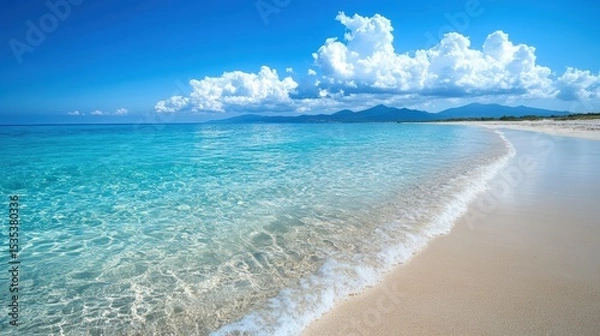 Obraz A pristine beach with clear turquoise water, gentle waves, white sand, under a bright blue sky with fluffy clouds and distant mountains.