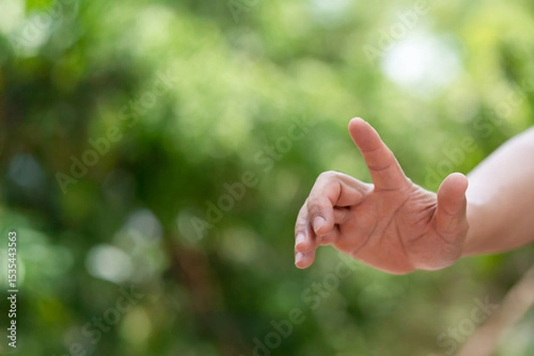 Fototapeta A hand reaching out against a soft green background, symbolizing connection, guidance, or the act of giving/receiving. Ideal for concepts of nature, help, or interaction.