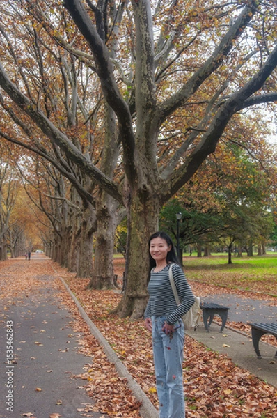 Obraz a happy chinese woman standing on fallen leaves in Flushing Meadows Corona Park