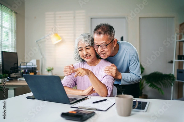 Obraz Senior Asian Couple Enjoying Retirement Planning Online Together at Home Using Laptop Computer Searching for Investment Ideas and Financial Security