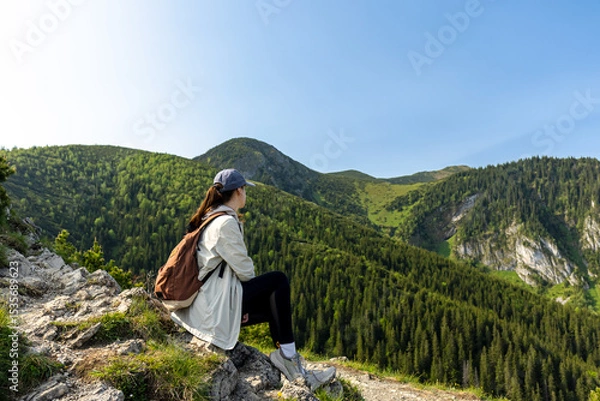 Fototapeta girl tourist sits on the edge of a cliff enjoying the view of the mountains and valley. travel and hiking in the mountains, Tatra Mountains, Poland
